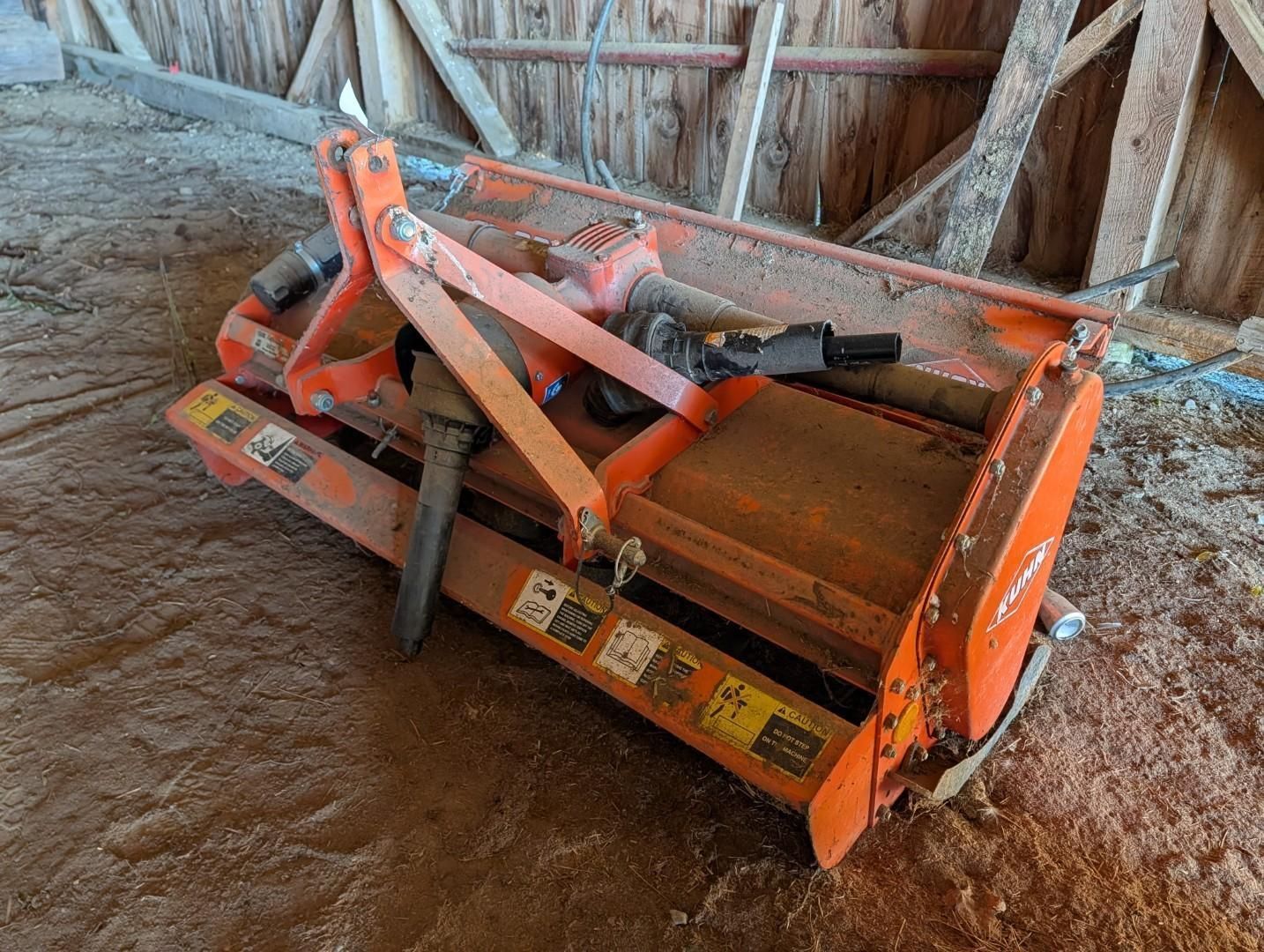 Orange tractor attachment in a dirt barn