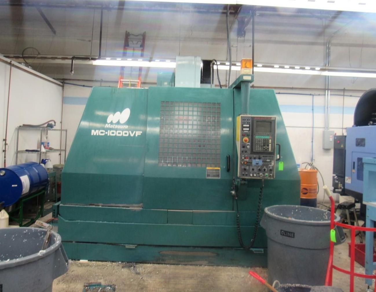 Green CNC machine in a workshop setting, with control panel.