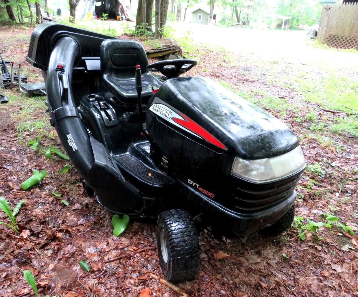 Black riding lawn mower with a collection system, outdoors.