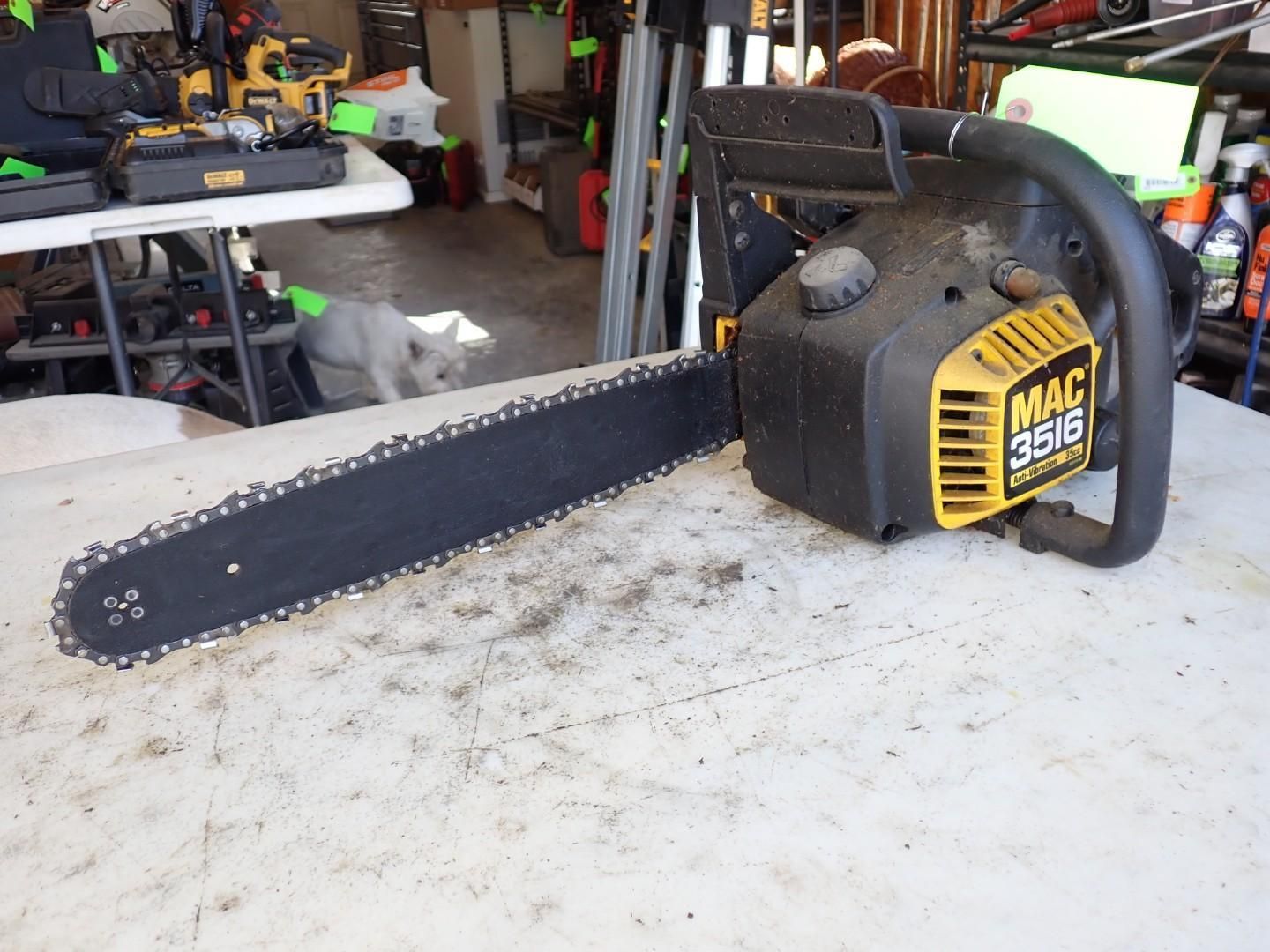 Black and yellow MAC chainsaw on a workbench in a garage, with a long bar and chain attached