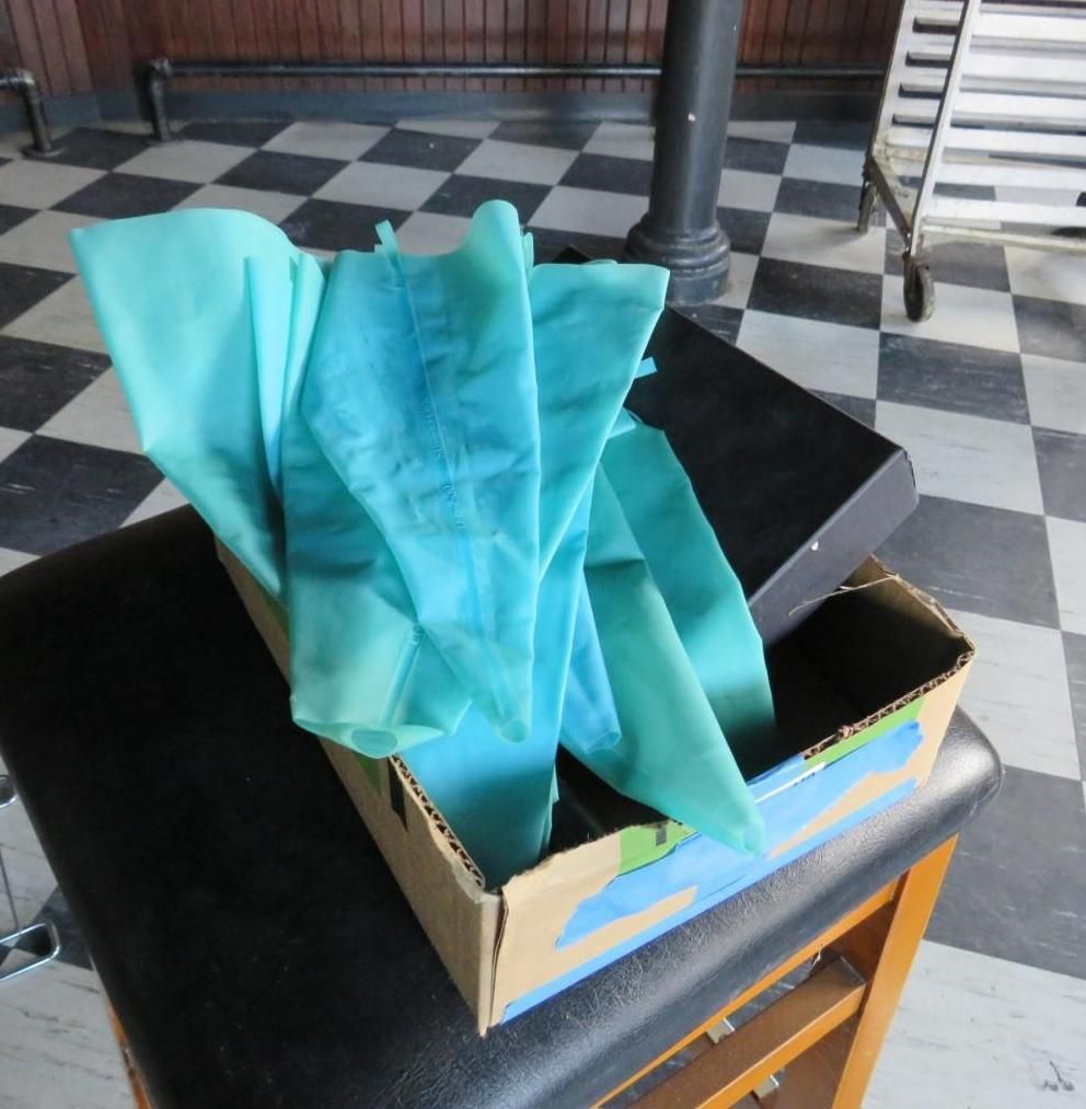 Box with blue fabric on a black chair, checkered floor in background.