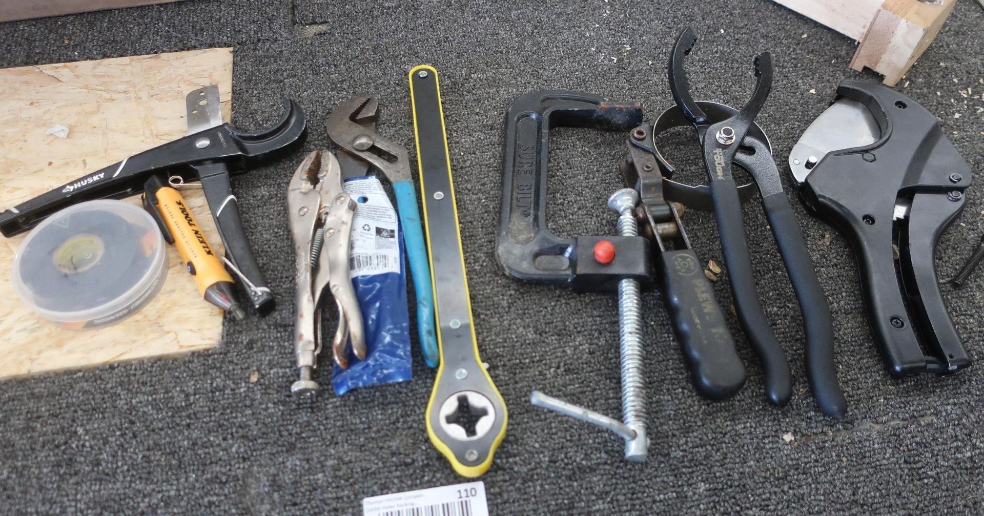 Tools: tape, knife, pliers, wrench, clamp, cutters, pipe cutter, on a dark surface.