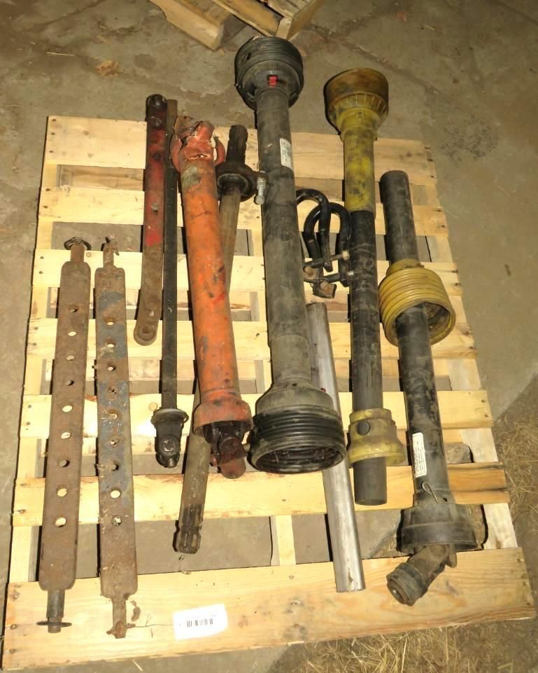 Assorted agricultural machine shafts and components on a wooden pallet.