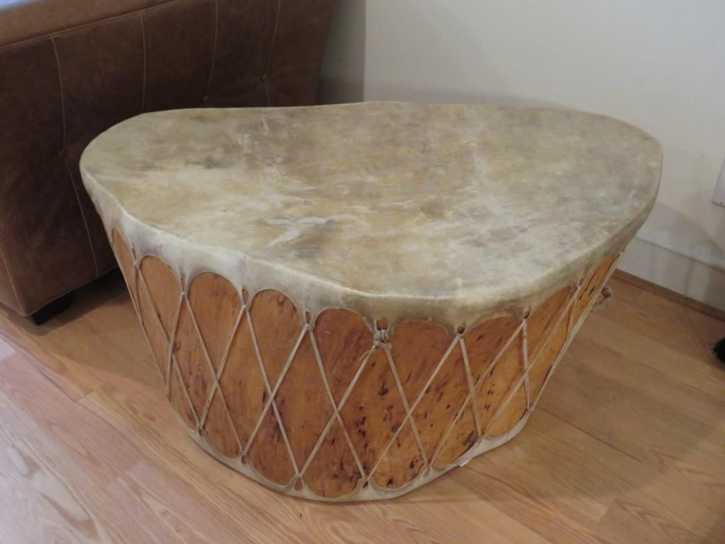 Large, tan, drum-like table with laced wooden sides and a light-colored, animal-hide top.