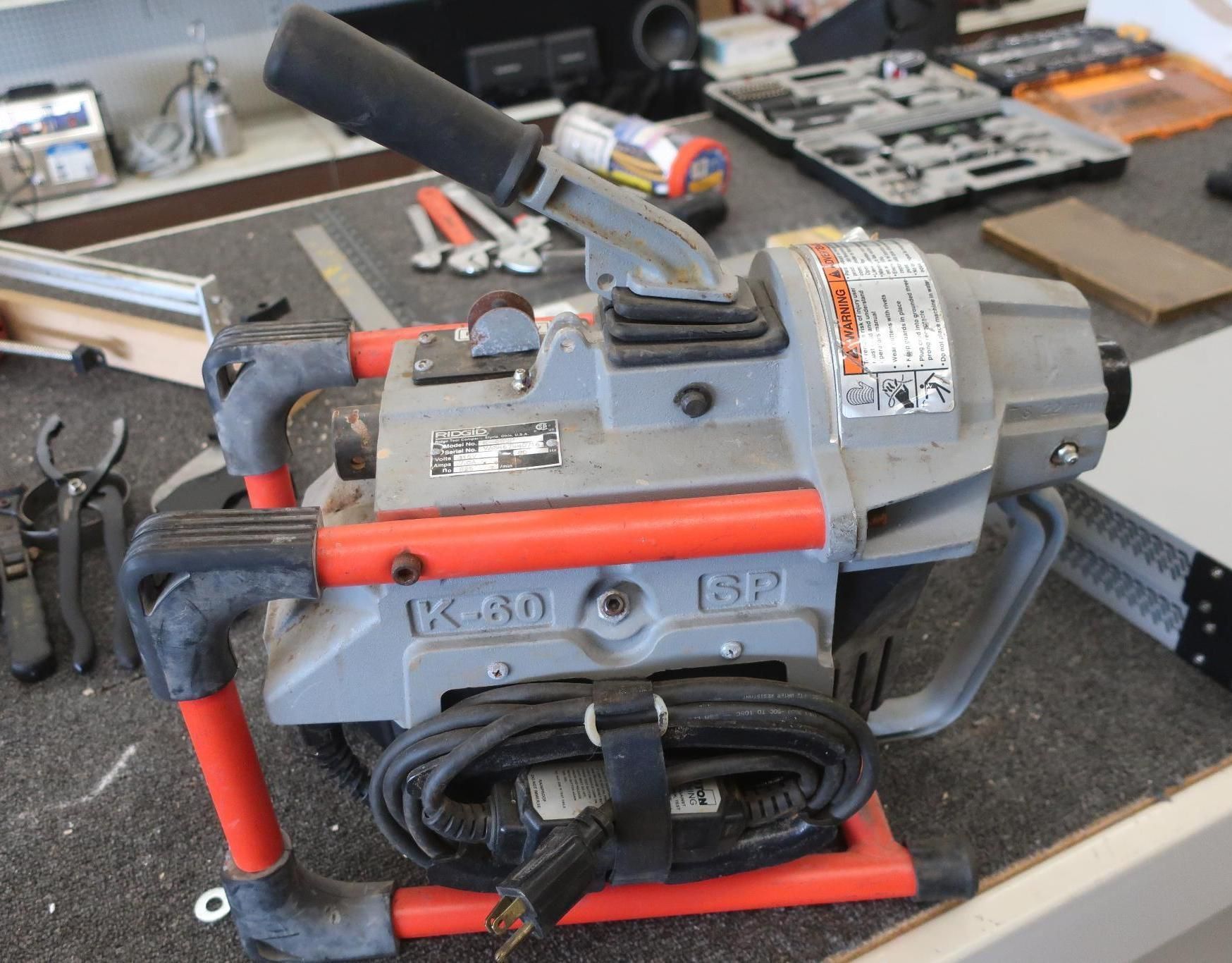 K-60 drain cleaning machine with red frame and black handle on a work surface.
