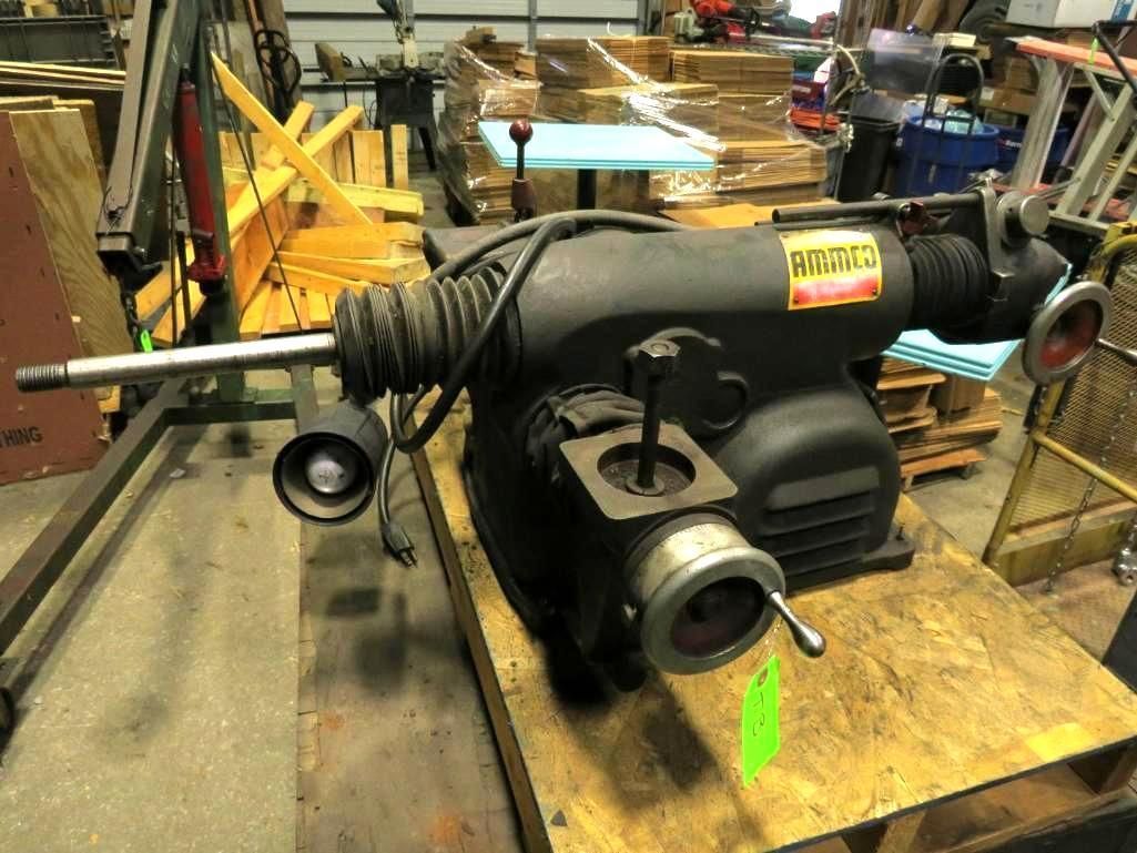 Black industrial machine with shafts and knobs on a wooden pallet.