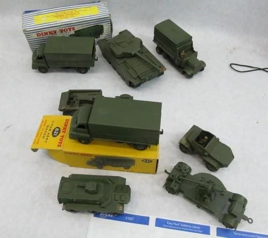 Collection of vintage green toy military vehicles, some with boxes, on a surface.