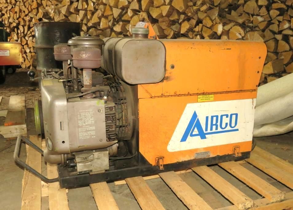 Orange and white AIRCO generator on a wooden pallet, with a woodpile background.