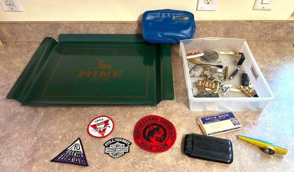 Green tray and assorted items: patches, case, knives, box, on countertop.