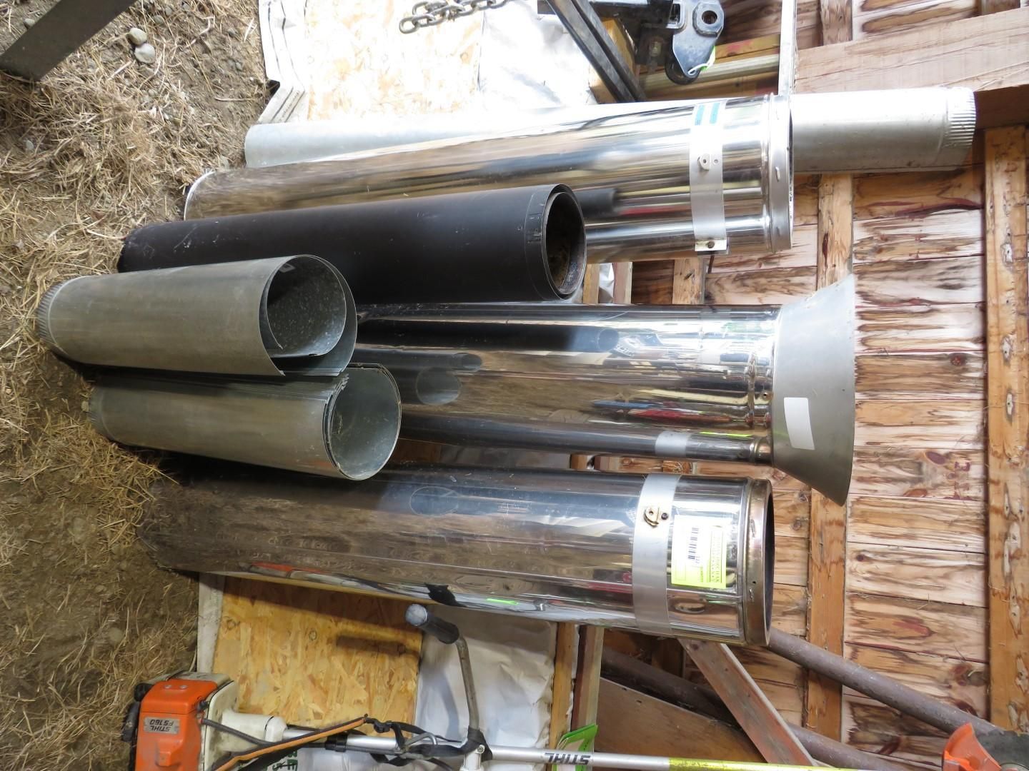 Metal exhaust pipes of varying sizes and colors rest on a wooden surface.