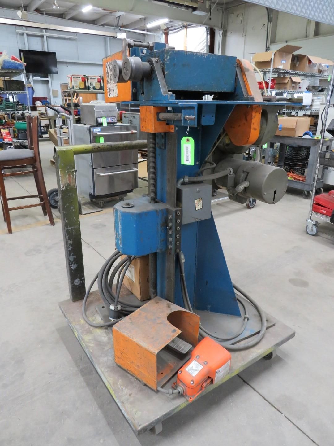 Blue and orange industrial machine on a gray cart in a warehouse.