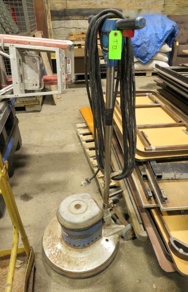 Floor buffer, metal and blue, with long black cord in a warehouse.
