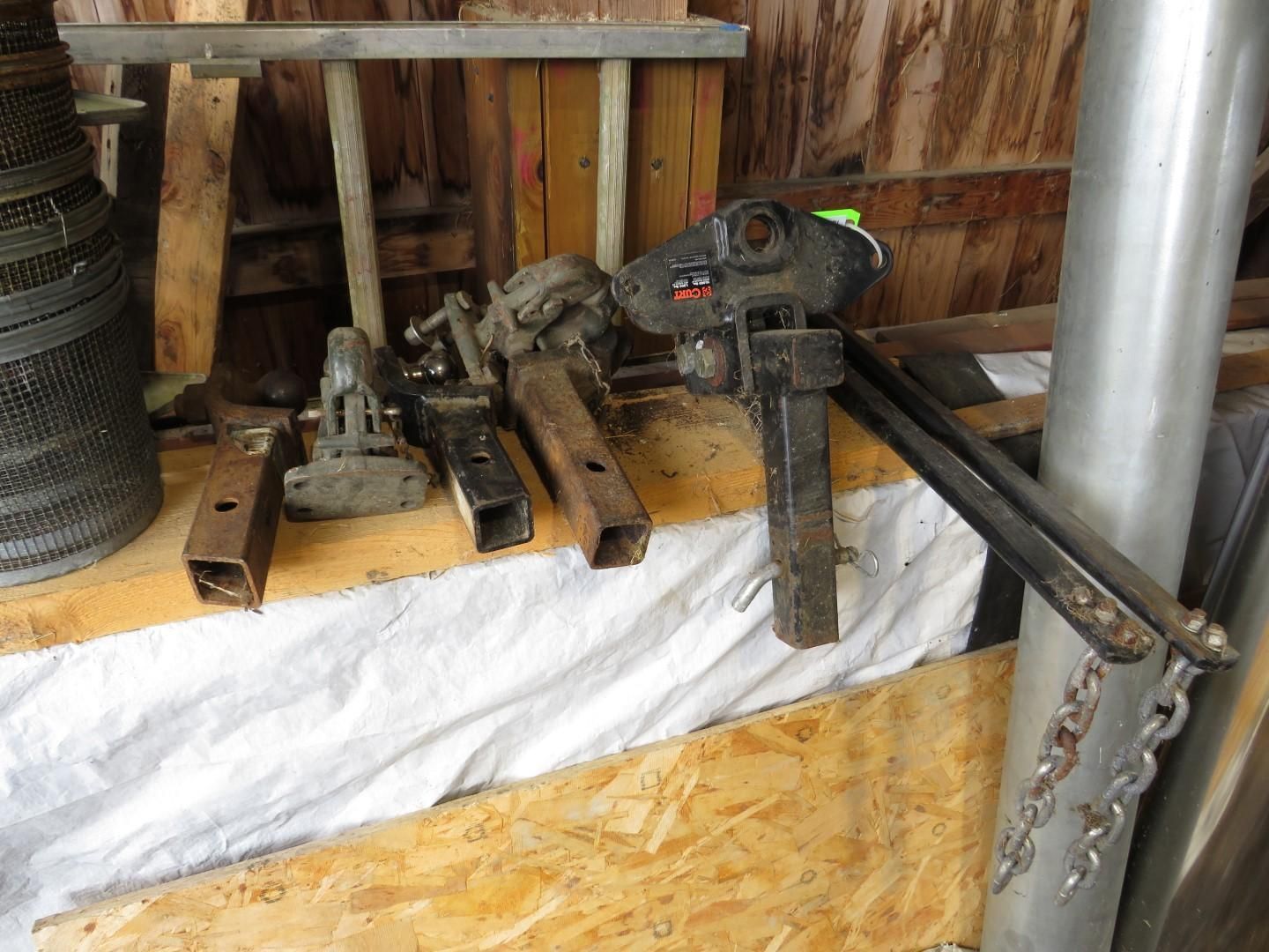 Various metal trailer hitch receivers on a shelf in a wooden shed.