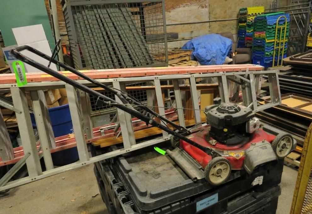 Ladder, lawnmower, and other equipment on top of a black storage bin.