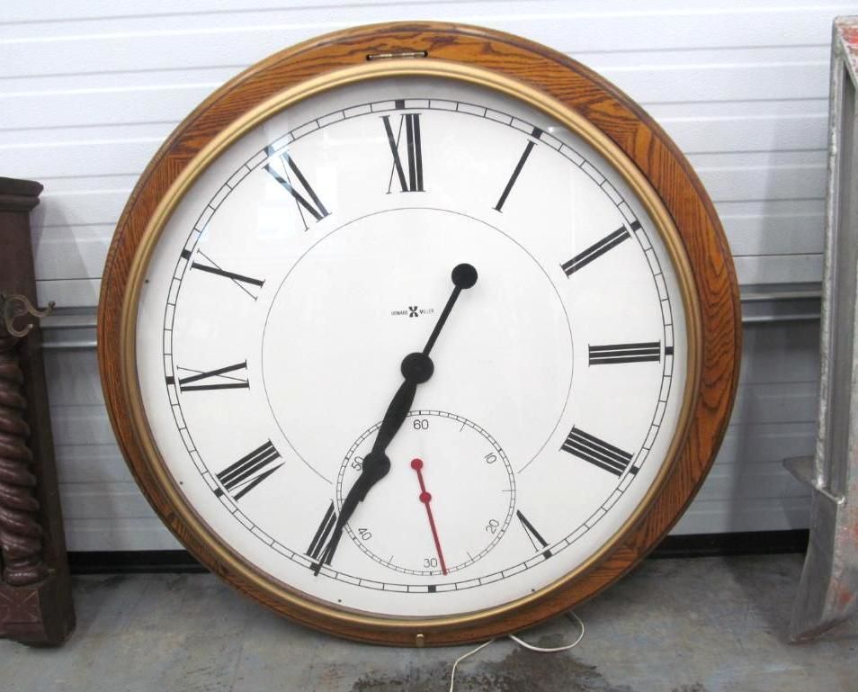 Large round clock with a white face, black Roman numerals, and a smaller seconds dial. Wooden frame.