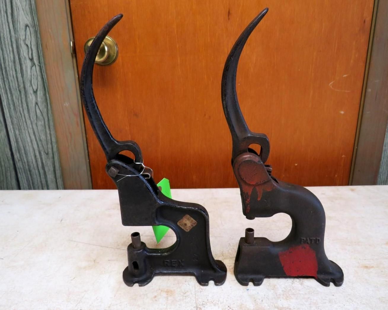 Two antique cast iron lever presses, black and red, on a wooden surface.