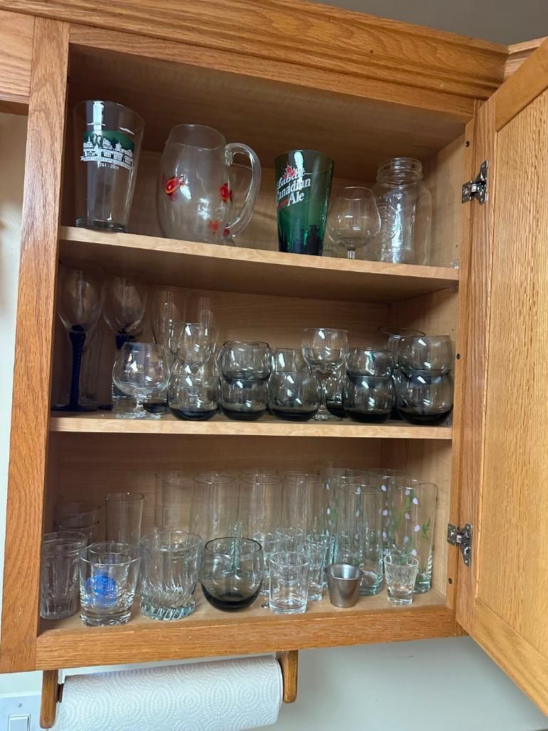 Wooden cabinet open, filled with various glassware on shelves.