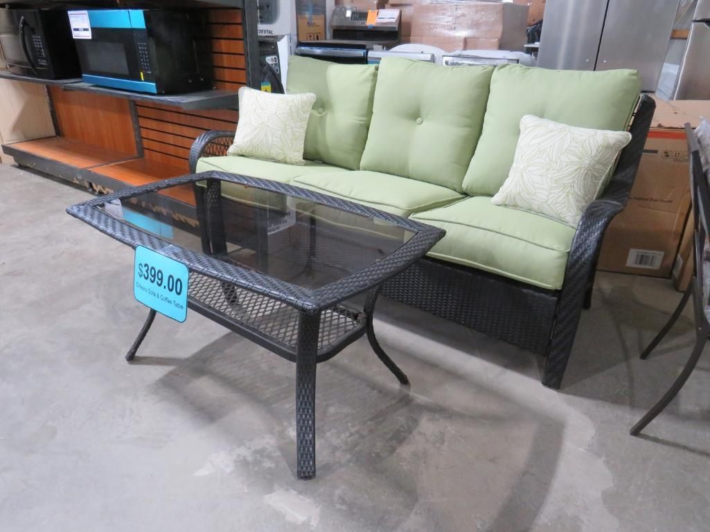 Outdoor furniture set with a green cushion sofa and glass-top table.