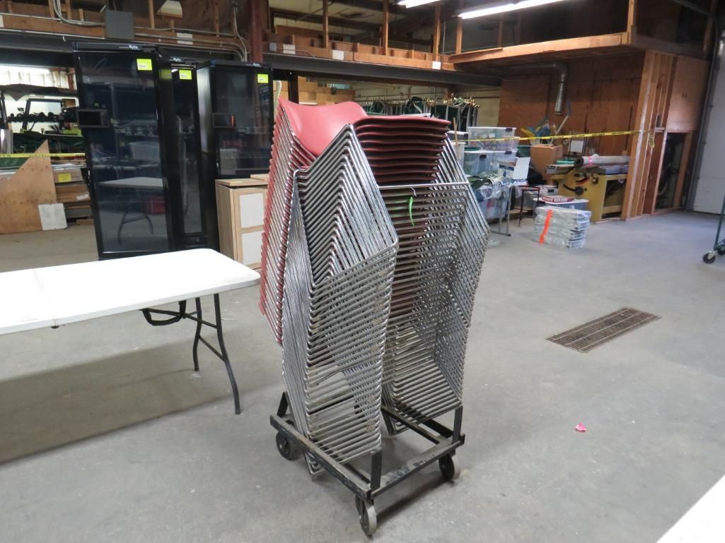 A metal cart holding stacked wire chairs in an industrial setting.