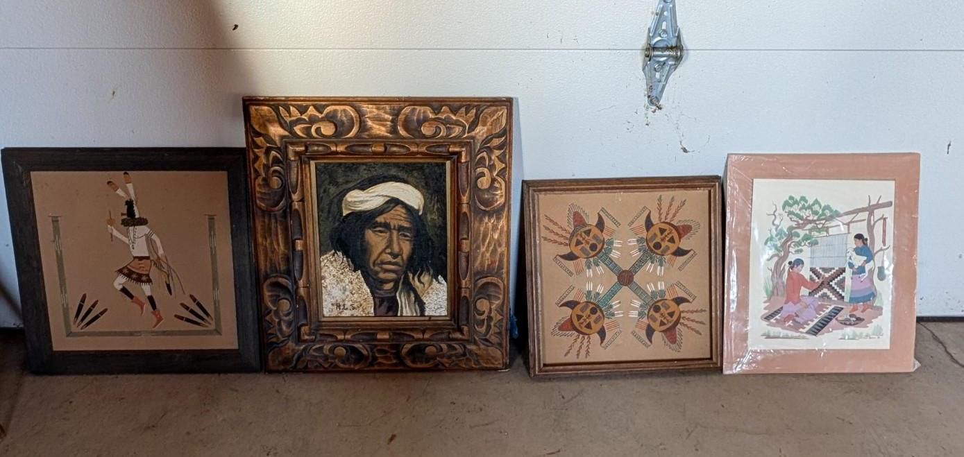 Four framed artworks leaning against a wall on a shelf, including a portrait and geometric designs