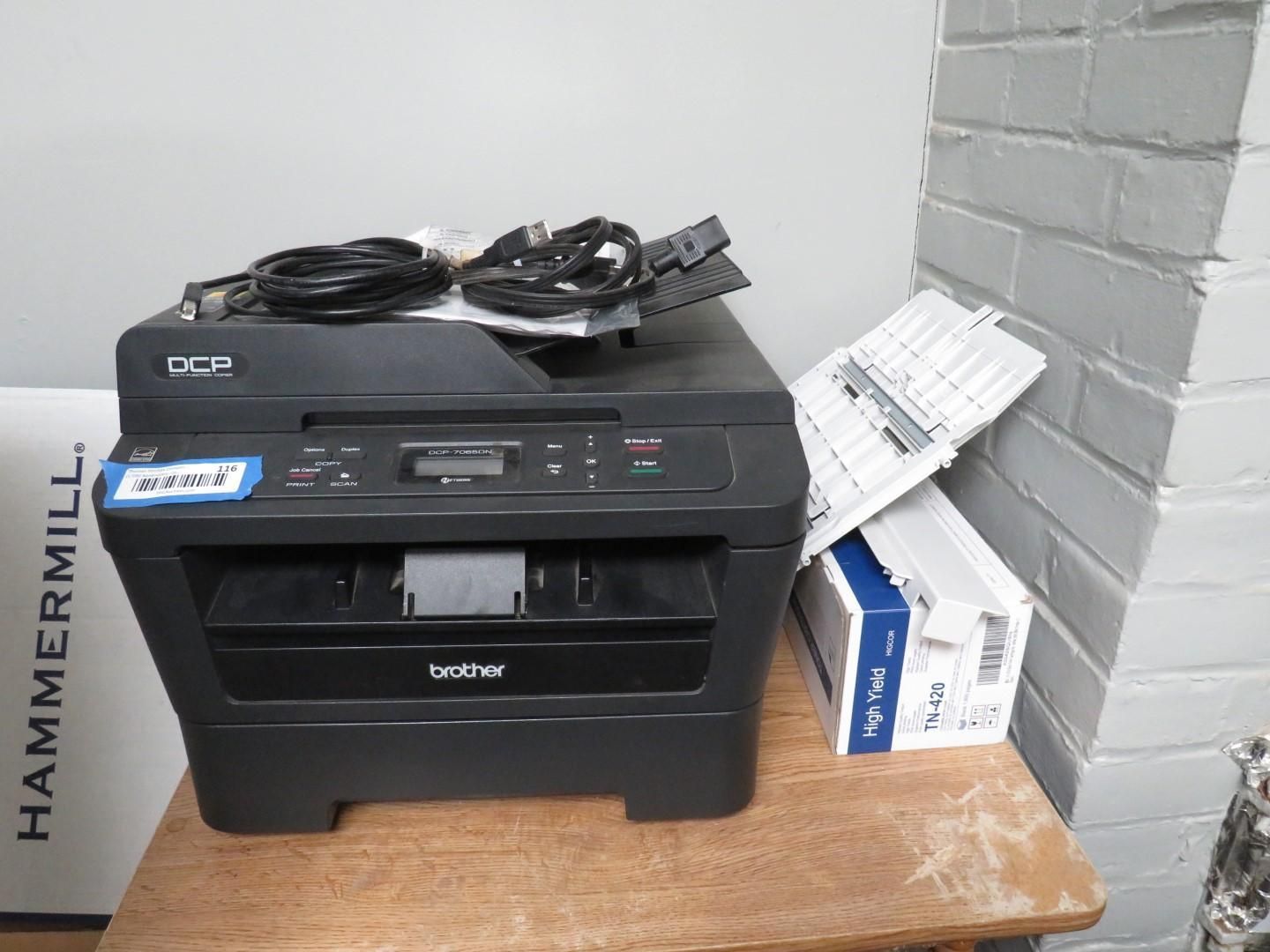 Black Brother printer with cables, paper tray, and a box, on a wooden table.