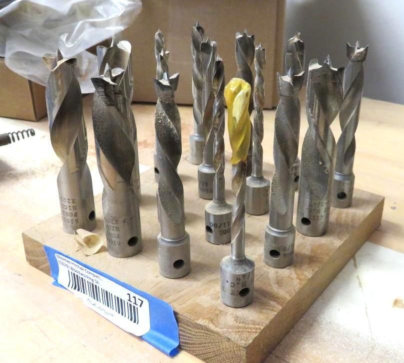 Set of metal drill bits arranged on a wooden block.