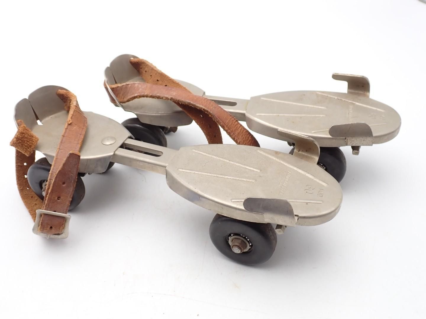 Pair of beige and brown antique wheeled roller skates on a white background