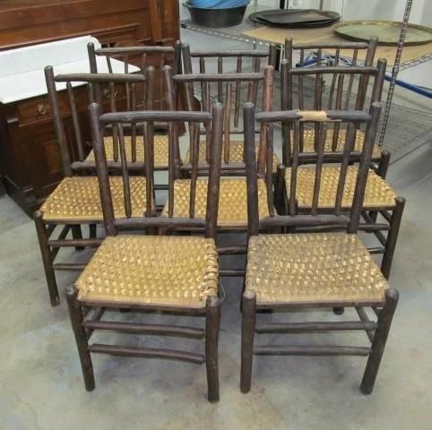 Six rustic wooden chairs with woven seats, arranged indoors.
