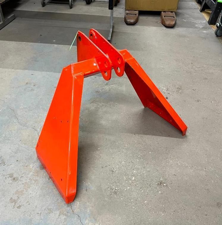 Orange, angular piece of machinery with three looped attachments, on a gray floor.