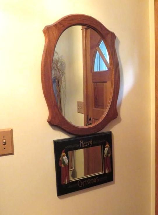 Oval wooden mirror above a small rectangular 