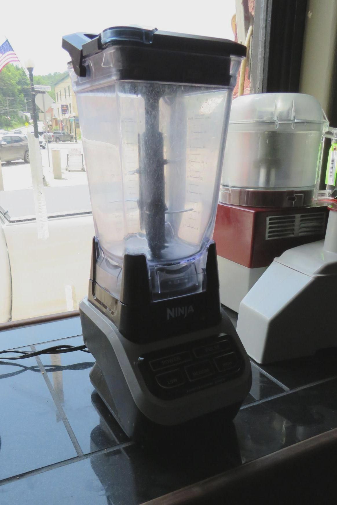 Ninja blender on a countertop, near a window, with other kitchen appliances visible.