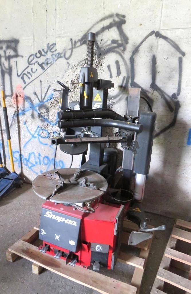 A Snap-on tire changer machine, red and black, on a pallet.