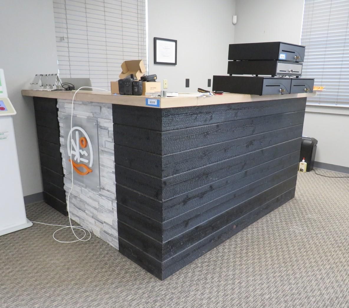 Reception desk with black wood paneling, stone accents, and electronics.
