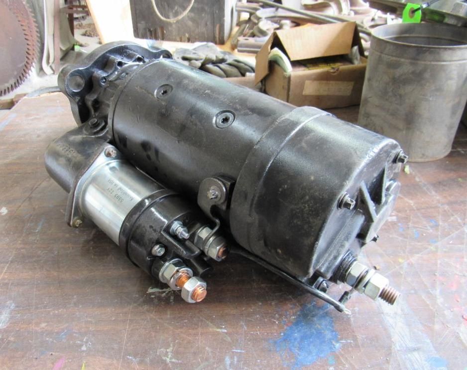 Black starter motor on a wooden surface, with attached solenoid.
