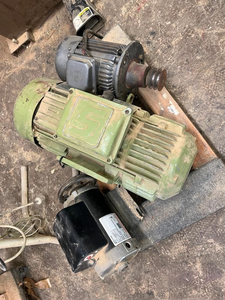 Three electric motors, one green, one gray, and one black, on a wooden surface.