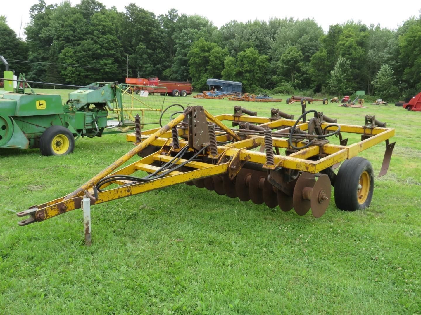 Yellow disc harrow in a grassy field.