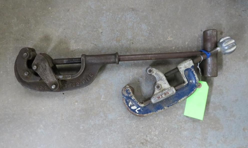 A pipe cutter tool on a gray surface with a blue tag.