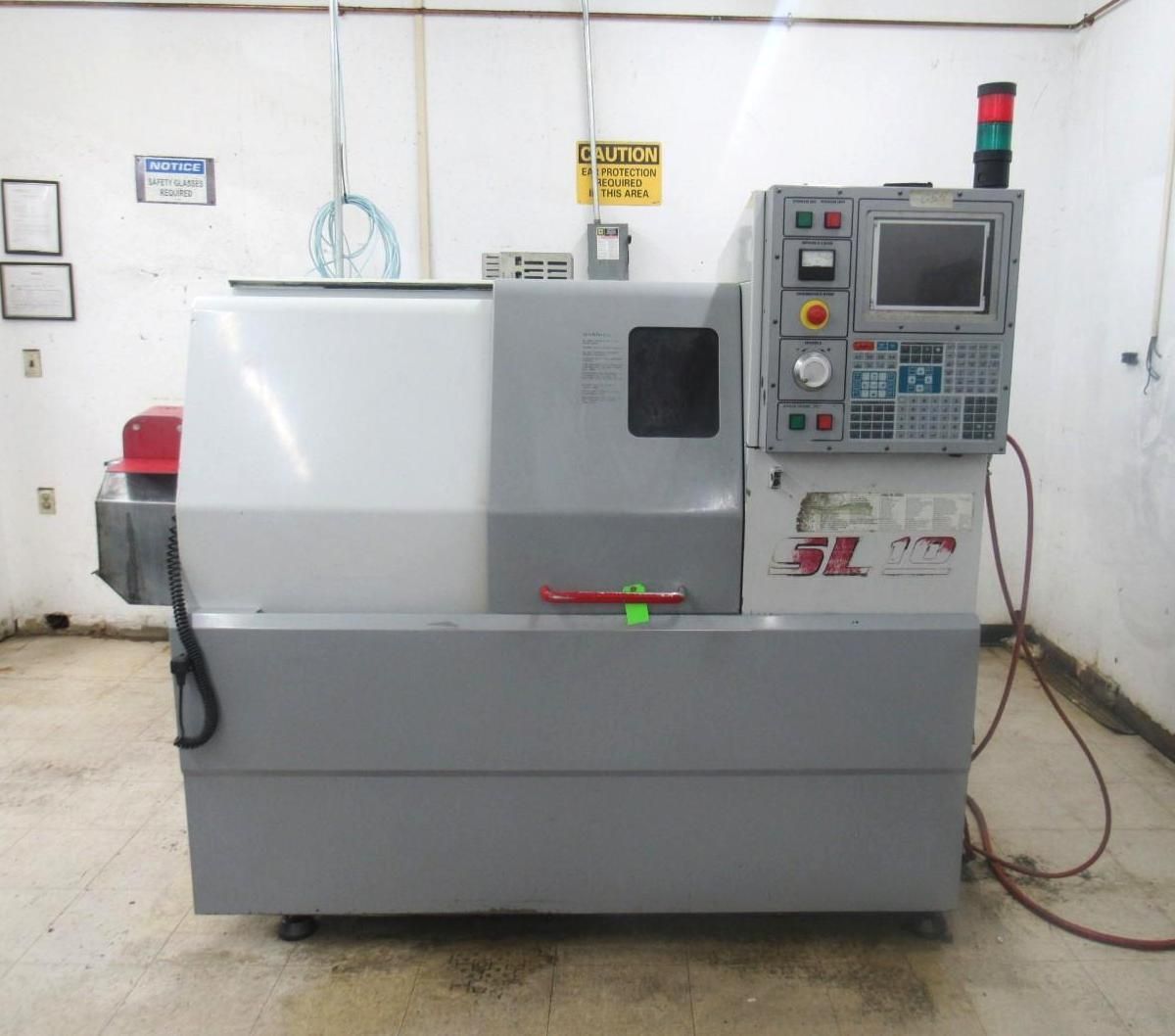 CNC lathe machine in a workshop setting, with control panel and red light.
