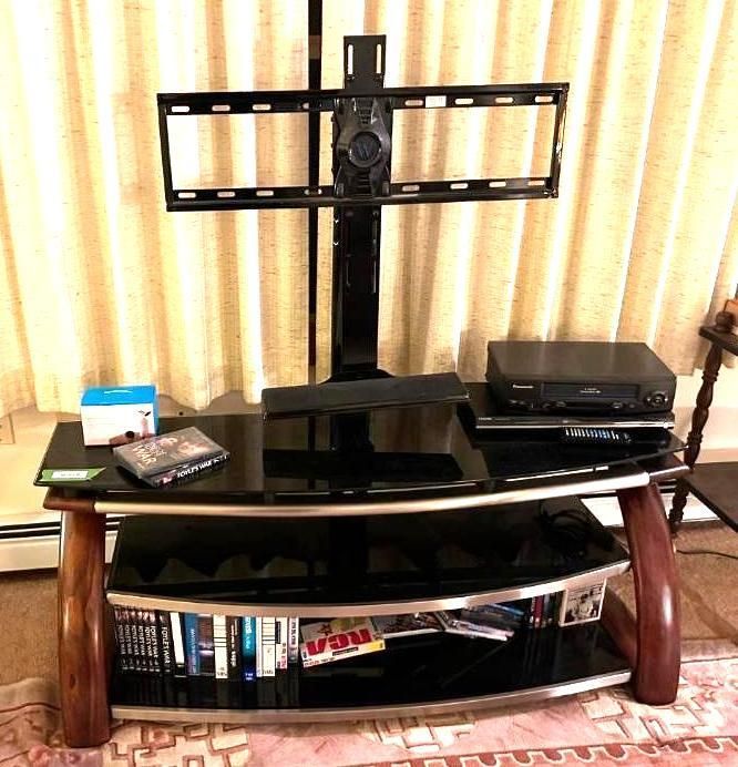TV stand with a mounted TV bracket, VCR, and media storage on shelves.