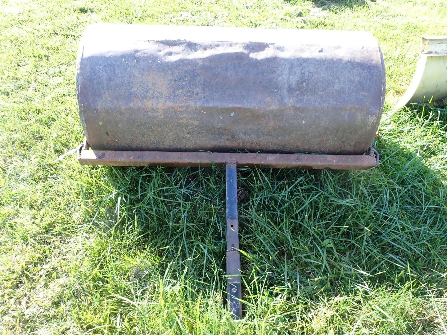 Black cylindrical grill on a metal stand sitting on grass outdoors