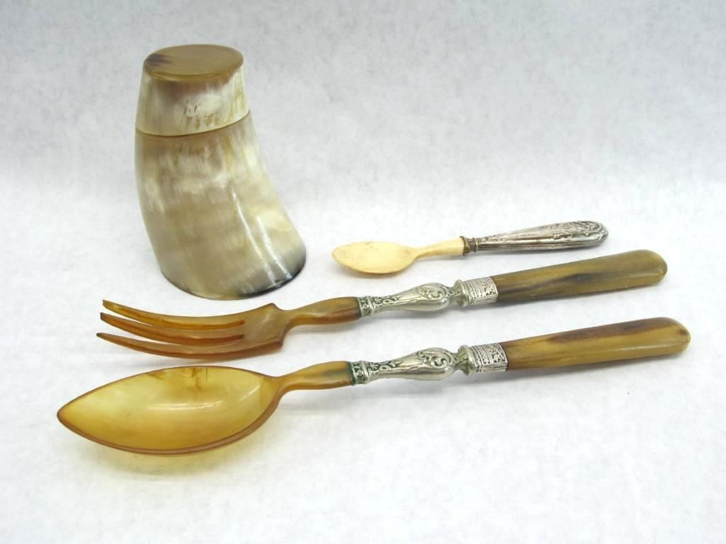 Horn container and cutlery set with silver accents: spoon, fork, and a small spoon.