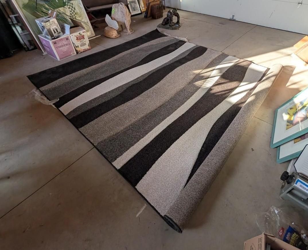 Striped black, gray, and white rug on a tiled floor in a sunlit room