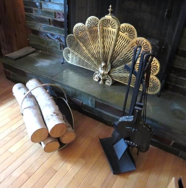 Fireplace with firewood, tools, and ornate gold screen.