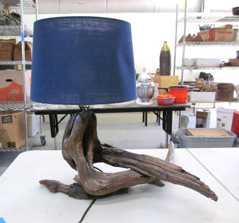 Driftwood lamp with a blue shade on a table.