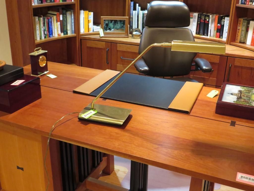 Wooden desk with lamp, chair, and bookshelves in a home office setting.