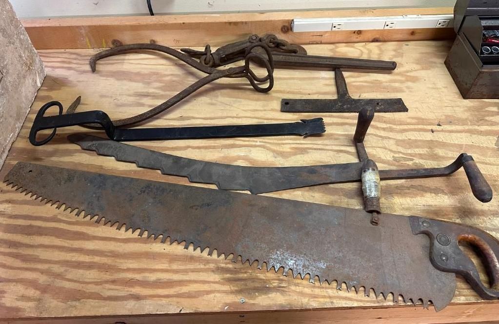 Several antique saws and tools on a wooden surface.