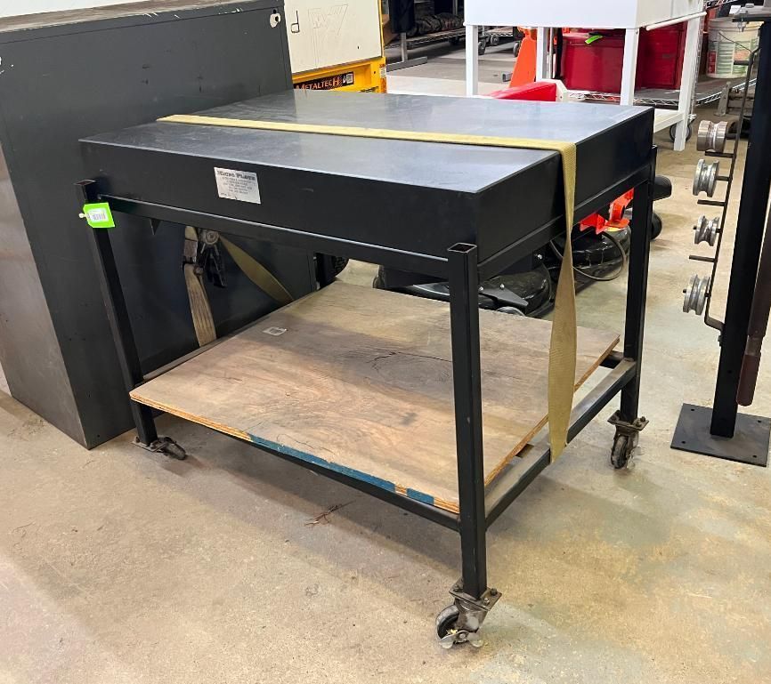 Black workbench on wheels with a lower shelf, a yellow strap, and a concrete floor.