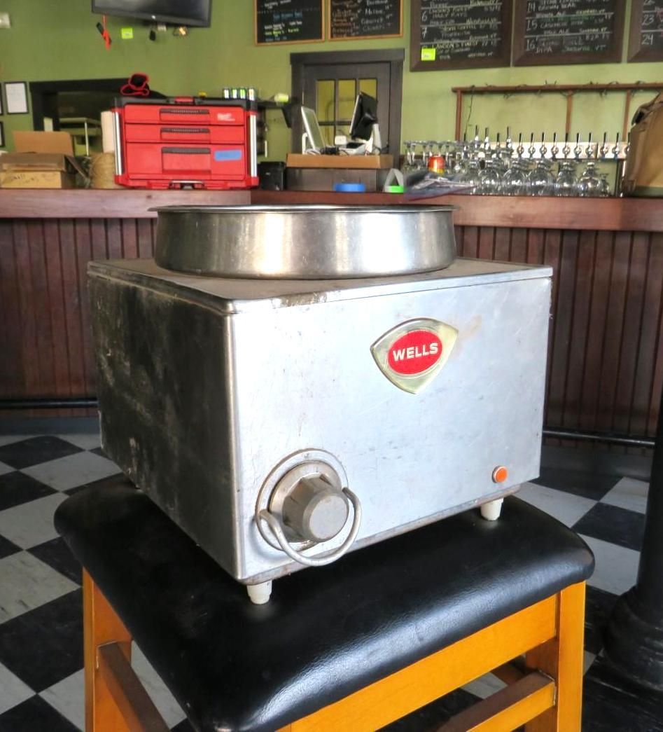A commercial cotton candy machine sits on a stool in a bar, with the brand name