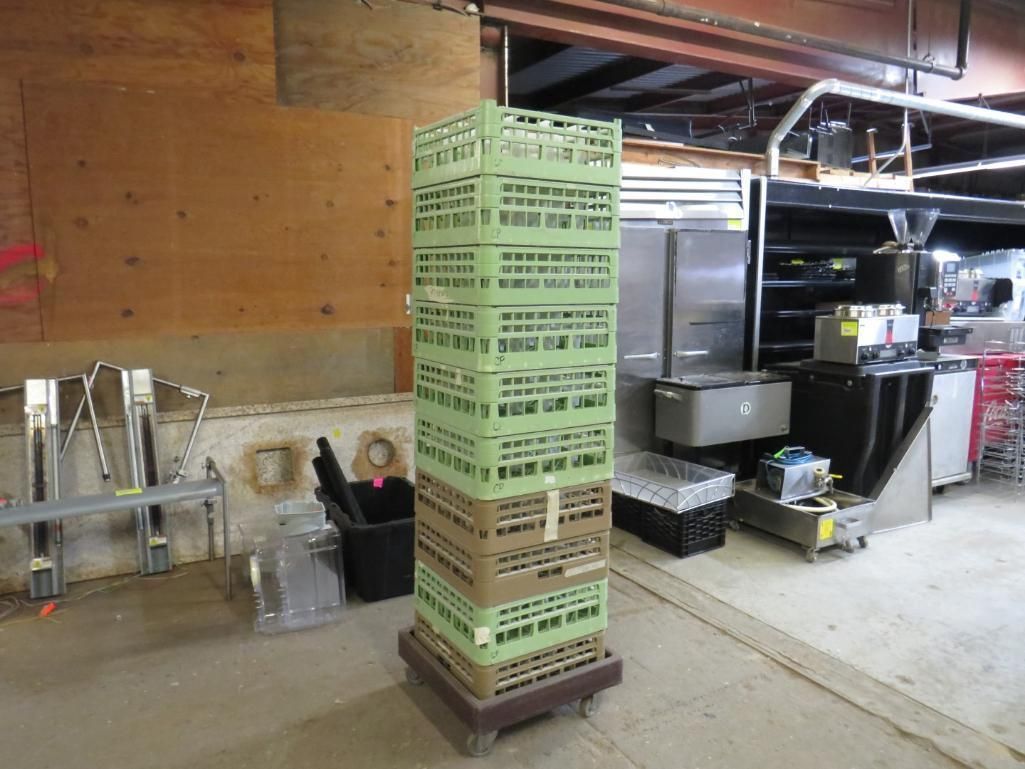 A tall stack of green crates on a wheeled base inside a commercial kitchen.