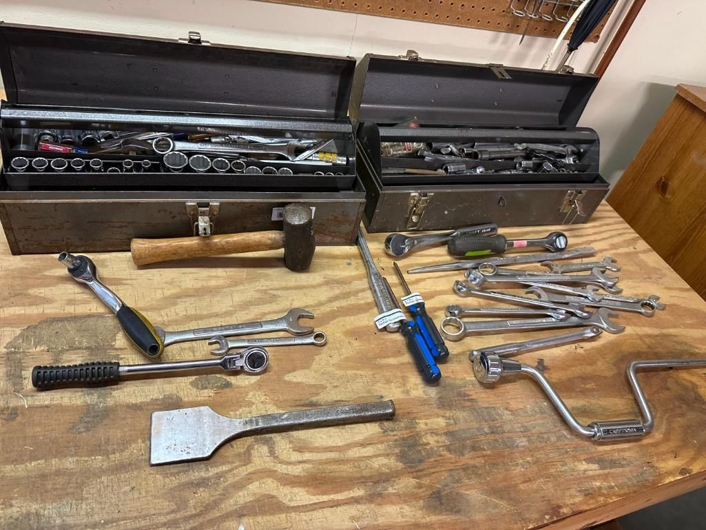 Two open toolboxes and various tools, including wrenches, hammers, and screwdrivers, on a wooden surface.